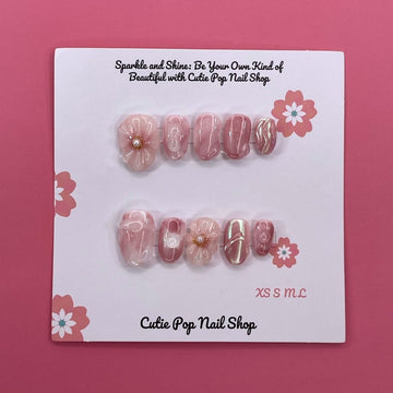 Sweet Pink press on nails by CutiePop Nail Shop featuring round shaped nails in soft pink tones, adorned with delicate flower designs and pearl centers for a cute and elegant finish.

