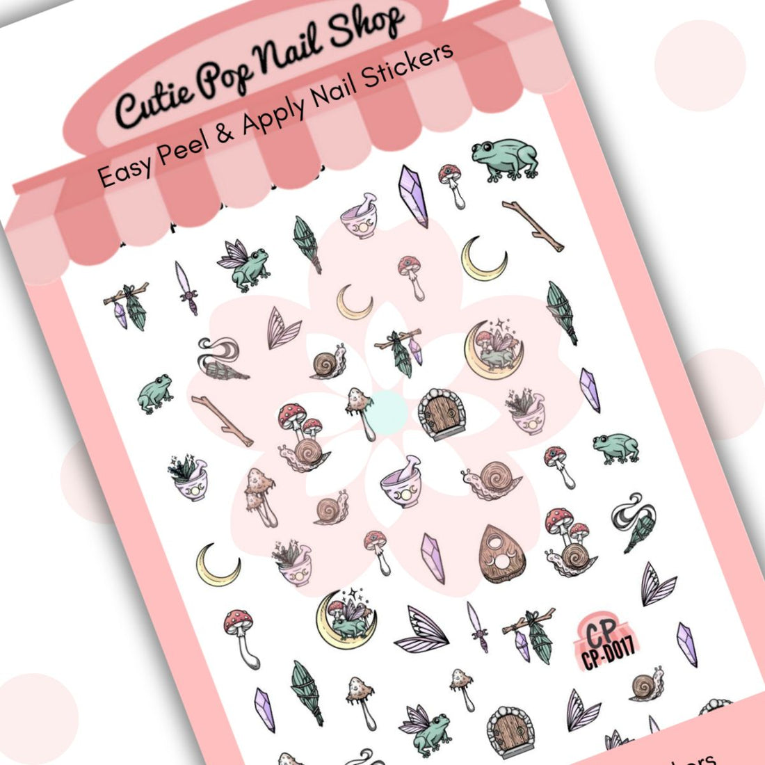 Cottage Core nail stickers by Cutie Pop Nail Shop featuring ultra thin 2D designs inspired by rural and nature themes, including crescent moons, chrysalises, frogs, fungi, herbs, gemstones, wings, sticks, swords, and tiny doors arranged on a pink edged display card labeled "Easy Peel & Apply Nail Stickers."